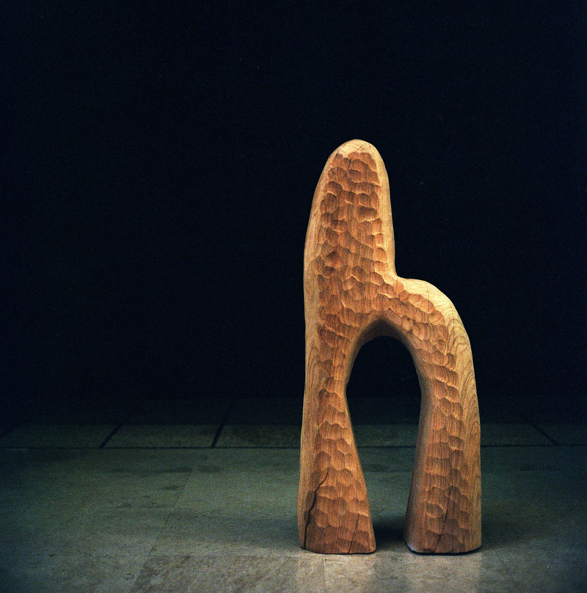 Sculpture en bois — figure arquée sur fond noir